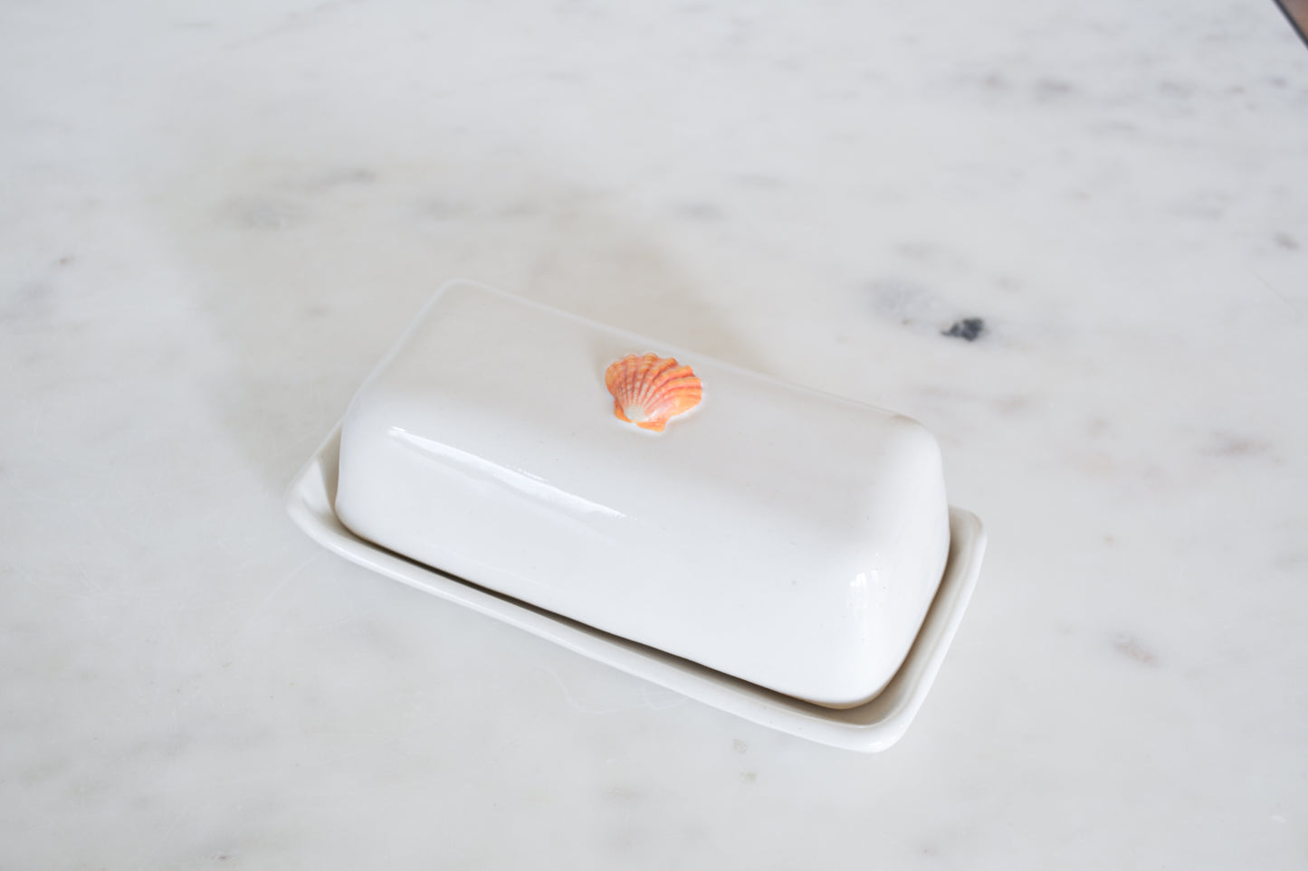 White butter dish with a shell on a marble surface